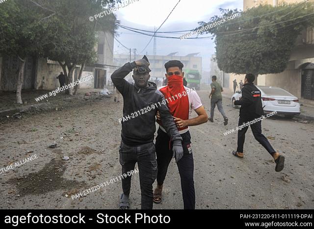 20 December 2023, Palestinian Territories, Rafah: A Palestinian man helps a survivor, following an Israeli strike on Rafah in the southern Gaza Strip