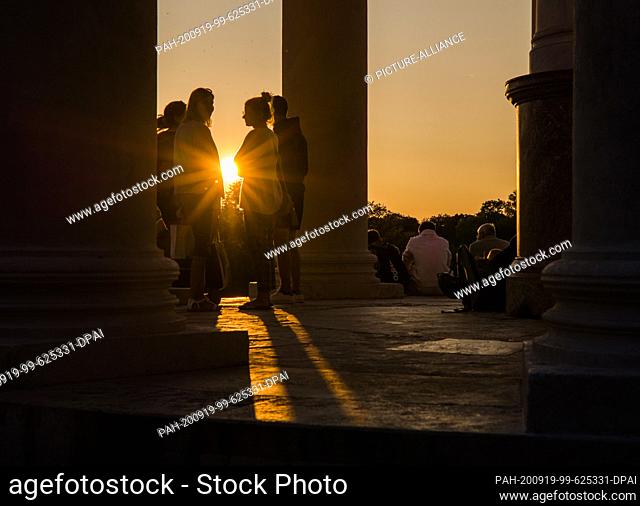 18 September 2020, Bavaria, Munich: Visitors to the English Garden enjoy the evening atmosphere at the ""Monopteros"" as the sun sets