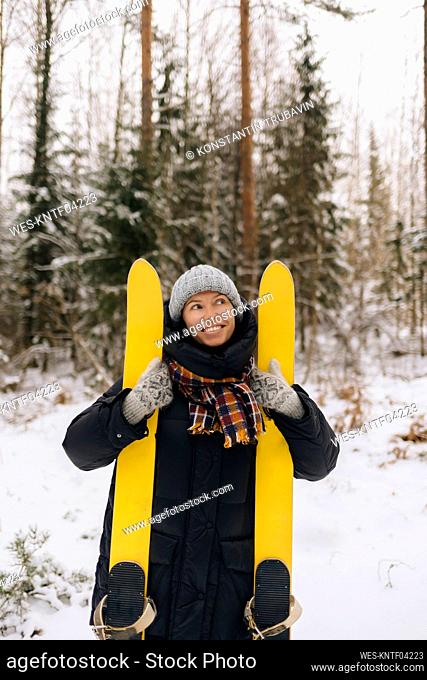 Portrait of smiling woman with skis in winter forest