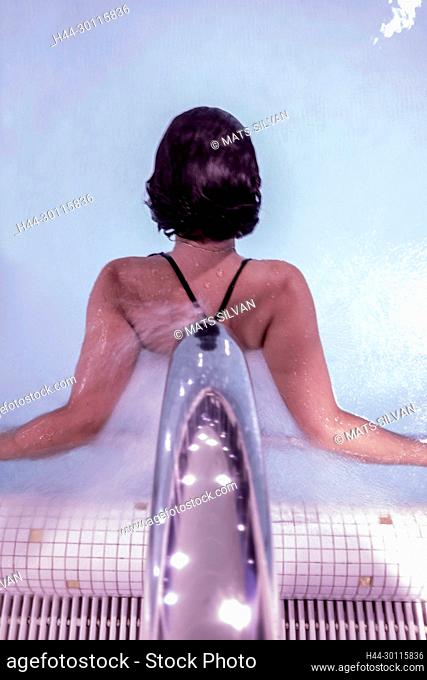 Woman Relaxing in a Hydro Massage Pool with Falling Water on Her Spine in Switzerland