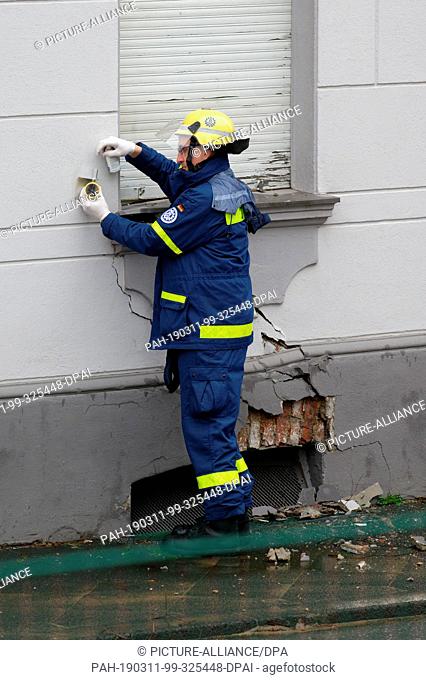 11 March 2019, North Rhine-Westphalia, Wuppertal: An employee of the German Federal Agency for Technical Relief attaches a measuring point to a house threatened...