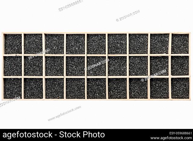 Black decorative sand distributed in a rectangular wooden box with square compartments