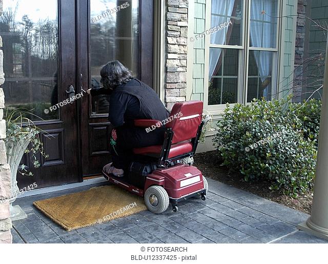 A woman using a wheelchair enters her home