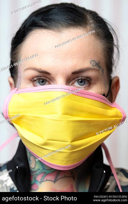 26 March 2020, Saxony, Zwickau: Daniela Beck, tattoo artist wears a self-stitched mouth guard. Beck and other women from Zwickau sew self-made mouthguards in...