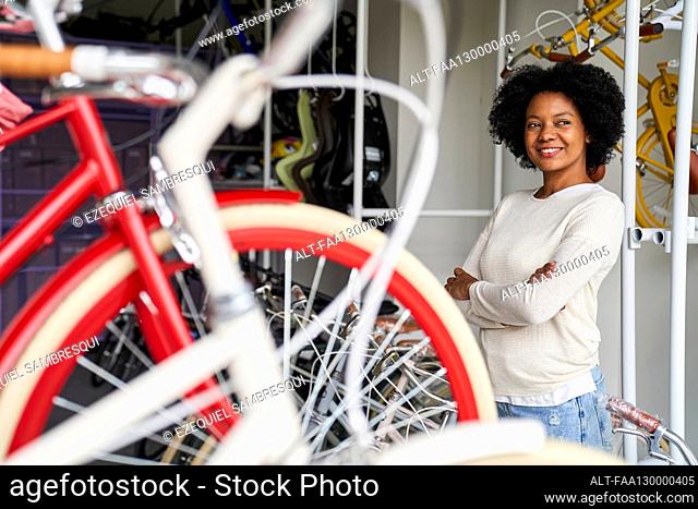 Mid-shot of female African-American shop owner standing in her store with her bicycles