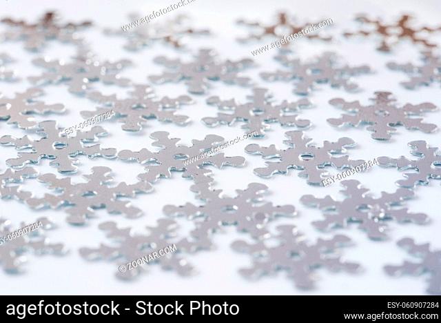 Christmas decoration of silver confetti snow flake against white background with nice boke. Close up confetti with shallow DOF