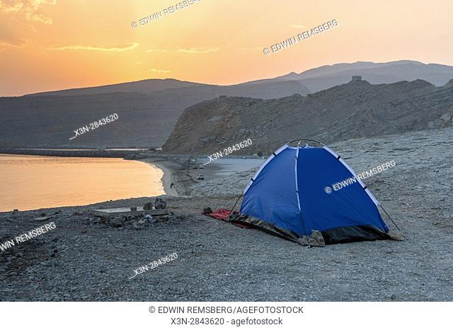 A pitched tent sits next to a body of water along the Musandam Peninsula in Khasab, Oman