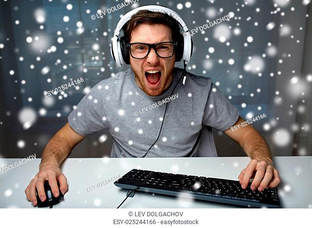 technology, gaming, entertainment, let's play and people concept - angry screaming young man in headset with pc computer playing game at home and streaming...