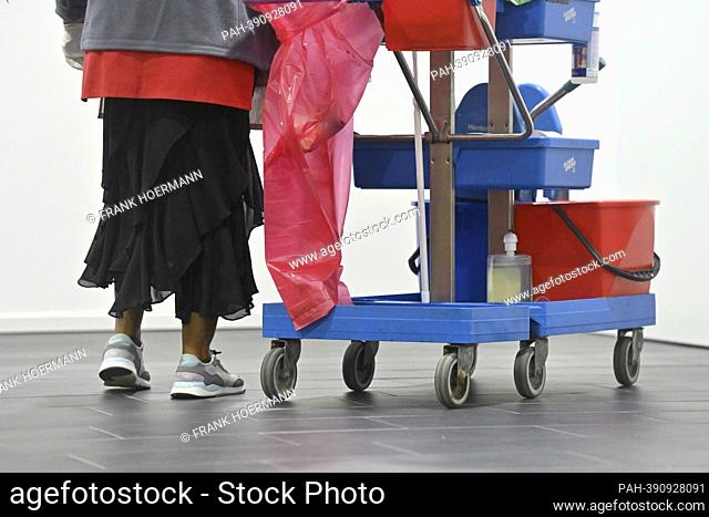 Theme photo, symbol photo; Cleaner at work with cleaning trolley, dark-skinned, colored cleaning lady, cleaning, minimum wage, , working hours, wages