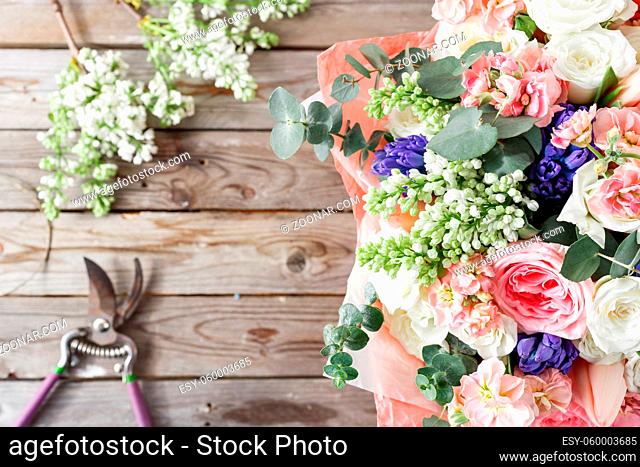 white lilac and mix flowers bouquet on wooden background. old rustic table, a coil of twine and garden ozhnitsy. top view