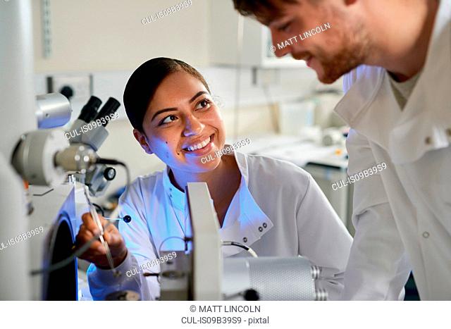Scientists in laboratory using scientific equipment smiling