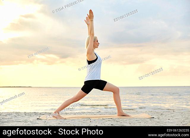 happy woman doing yoga warrior pose on beach