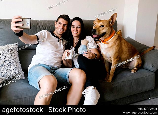 Couple taking selfie with dog at home