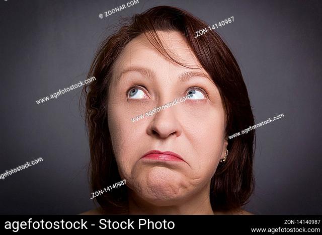 Woman grimaces in front of camera on black background