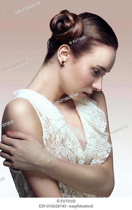 porttrait of pretty brunette girl with elegant creative hair-style in romantic pose wearing white lace shirt