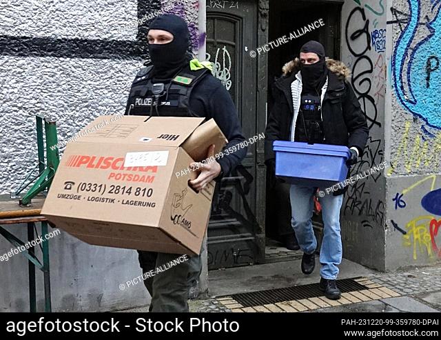 20 December 2023, Berlin: Police officers carry boxes out of an apartment building during a search operation. The Berlin police raided a left-wing feminist...