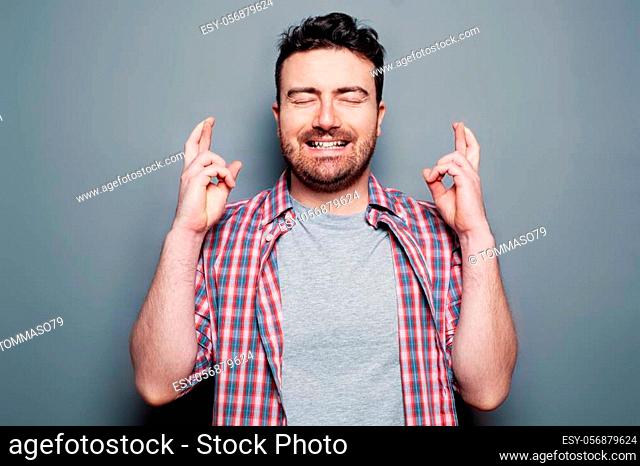 Man with fingers crossed hoping for good news