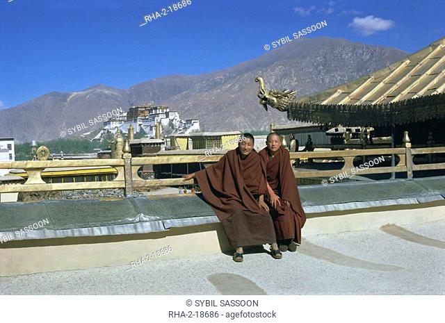 Two Tibetan Buddhist monks at Jokhang temple, with the Potala palace behind, Lhasa, Tibet, China, Asia