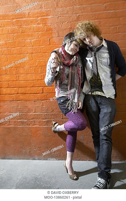 Young couple leaning on brick wall