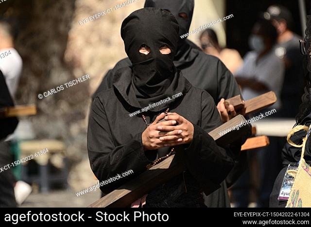 TAXCO, MEXICO - APR 15, 2022: A woman penitent wears a black hood known as a capirotte and a black robe, while takes part during Good Friday of the Holy Week...
