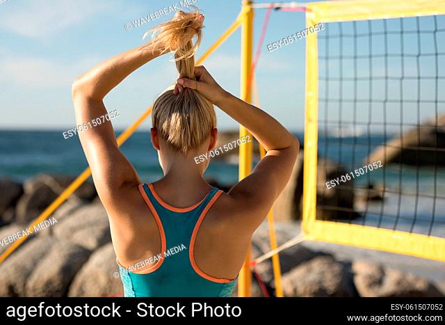 Female volleyball player tie her hair on the beach