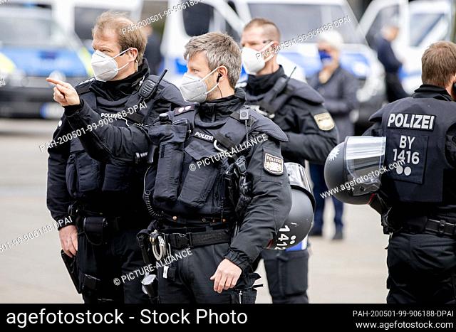01 May 2020, Berlin: A policeman wearing a breathing mask is standing next to other officers at a rally of various trade union activists at Alexanderplatz to...