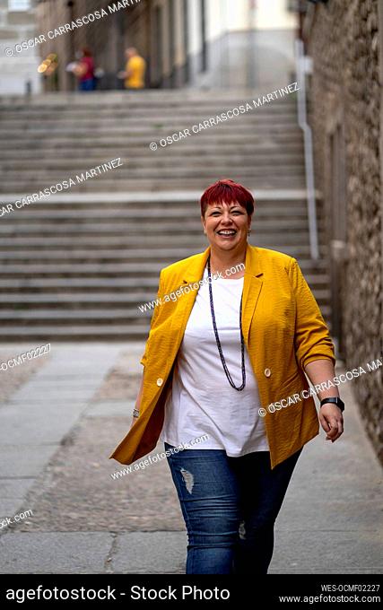 Mature woman laughing while walking on footpath