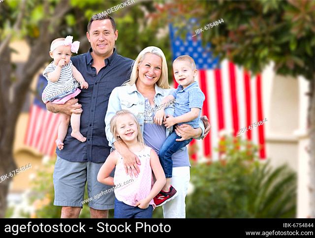 Happy young caucasian family in front of houses with american flags