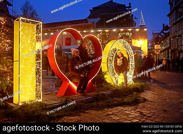02 December 2023, Saxony-Anhalt, Quedlinburg: Visitors have their photo taken in front of illuminated Advent decorations