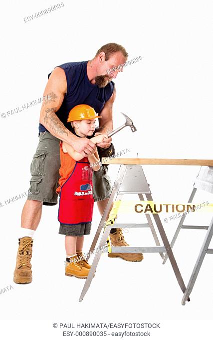 Caucasian father teaching his cute son how to hild a hammer and hit a nail into a wooden plank, isolated