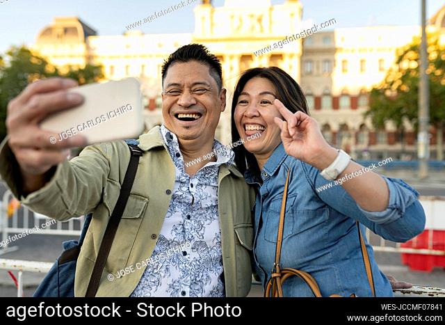 Happy mature couple taking selfie in front of building