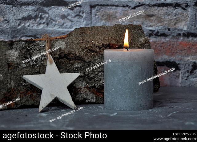Brennende Kerze, Stern und Holzscheit vor Ziegelmauer - Burning candle, star and wood billet in front of brick wall