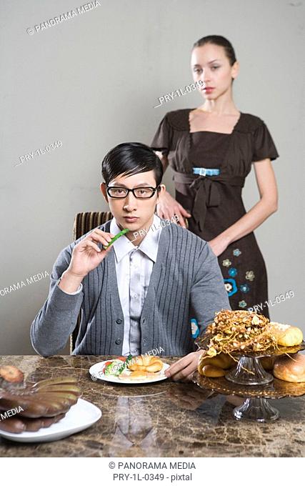 Husband sitting at breakfast table and wife standing behind