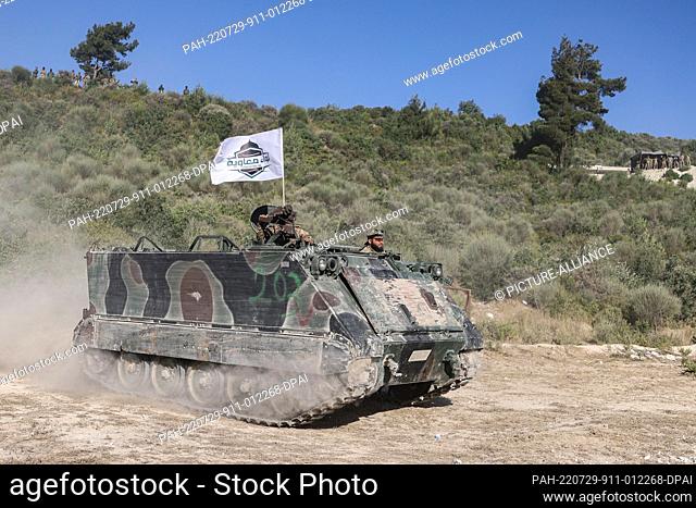 29 July 2022, Syria, Idlib City: Fighters of Hay'at Tahrir al-Sham (Levant Liberation Committee or HTS) opposition militant group ride an armoured personnel...