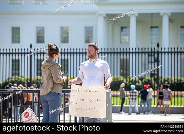 Bill Nadler, of Washington, DC, holds his protest sign as people go about their daily life while visiting outside the White House in Washington, DC, Tuesday