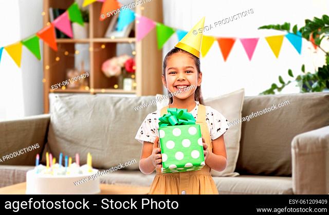 happy girl in party hat with birthday gift at home