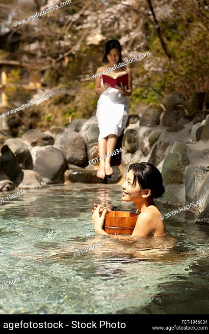 Happy young women relaxing at sunny pool in Onsen