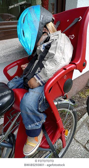little boy having returned from a bicycle tour: two drinking, one sleeping in the child seat on a bike