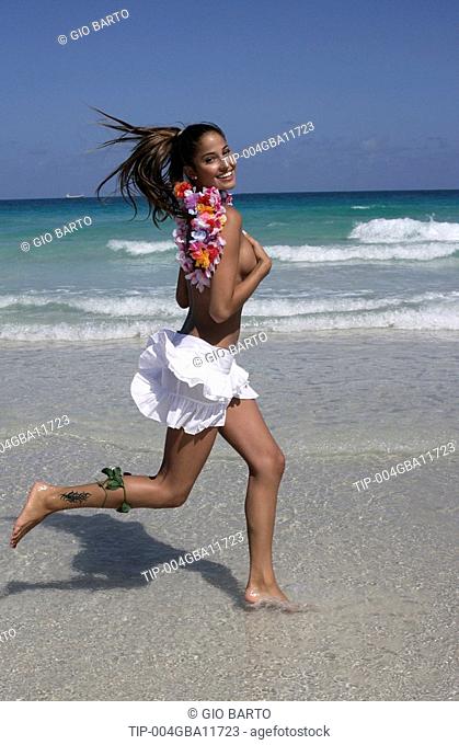 Topless woman running on beach