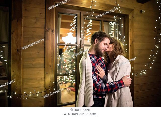 Young couple wrapped in a blanket cuddling outdoors at night