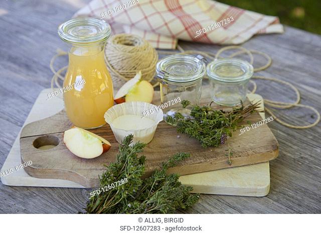 Ingredients and glass jars for thyme jelly with apple juice on a wooden table
