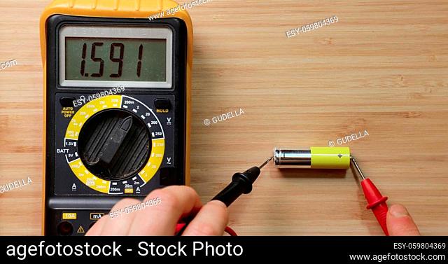 Testing AA battery cell with digital multimeter tool, voltage check showing good value, battery is still new and full charge