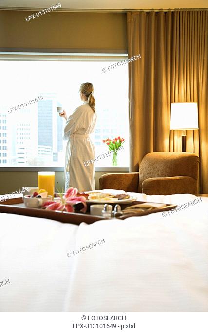 Bed in breakfast tray laying on bed with mid-adult woman in background