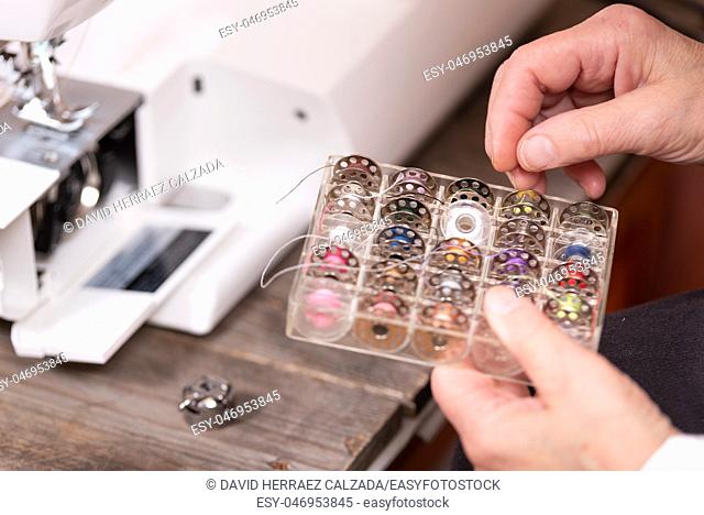 Close up on seamstress hands choosing threads for electrical sewing machine