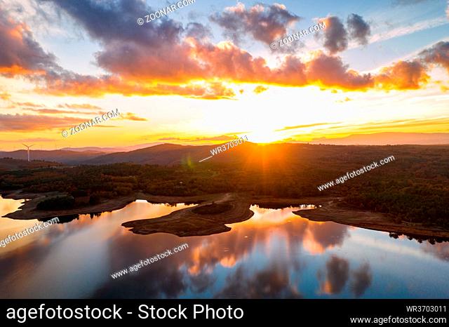 Drone aerial view of a lake reservoir of a dam with perfect reflection on the water of the sunset in Sabugal, Portugal