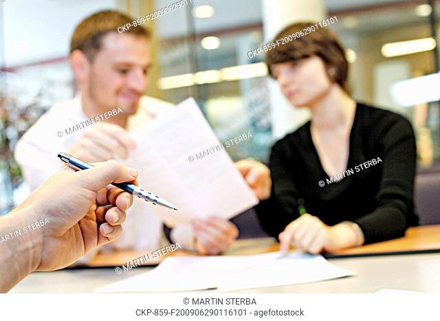young man, woman, couple, clients, meeting in a bank, contract form, pen, sign