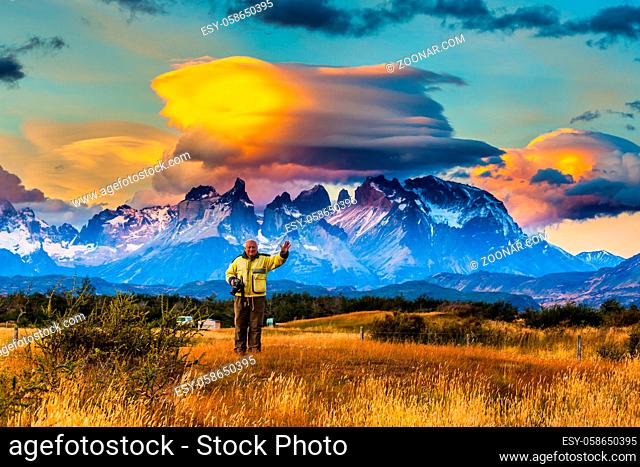 Snow-covered rocks of Los Cuernos and cumulus clouds in the orange sunset. The concept of extreme and active tourism. Torres del Paine National Park