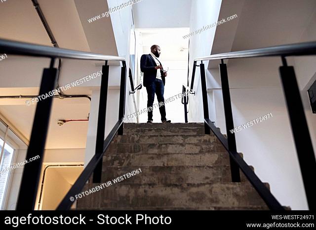 Businessman standing on stairs looking back through door