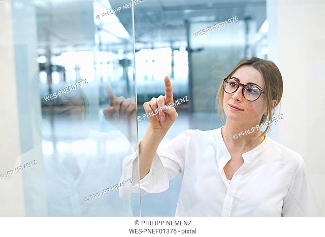 Young businesswoman touching virtual touchscreen