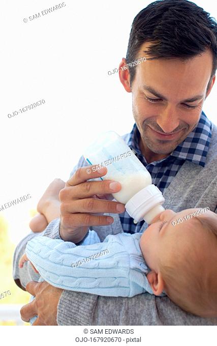 Father bottle feeding baby outdoors